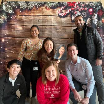 A group of people smiling in front of a holiday photo backdrop.