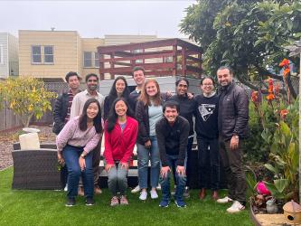 A smiling group of people standing together in a backyard.